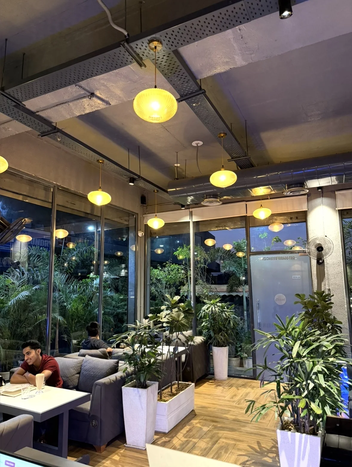 Cozy café seating beside glass windows and lush plants